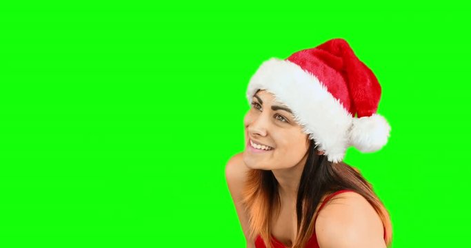 Pretty girl in santa hat blowing over hands on green screen