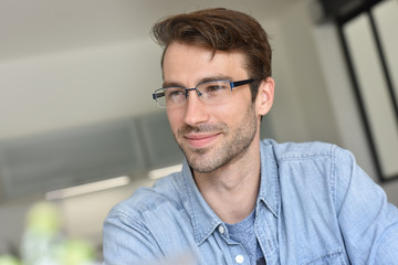 Obraz premium Casual smiling guy with eyeglasses sitting at home