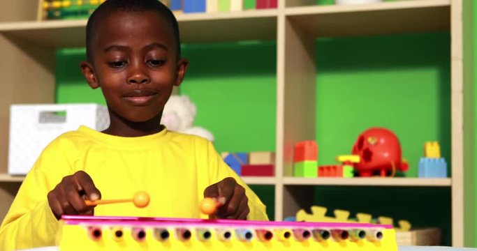 Cute little boy playing xylophone in classroom