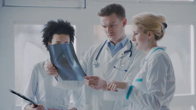 Healthcare, medical: Group of multi-ethnic doctors discussing and looking x-ray in a clinic or hospital. UHD 4K