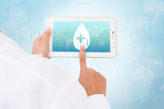 Doctor hand touch screen Donate blood Blood Drop symbol on a tablet. medical icon