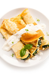 Crepes with spinach and feta cheese on white background 
