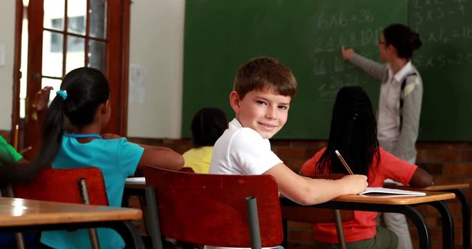 Little boy turning to smile at camera during class in elementary school