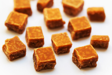 Salted caramel pieces and sea salt close up over white backgroun