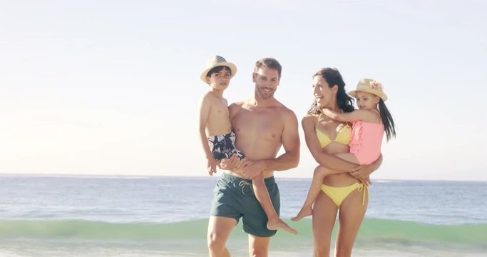 Happy parents carrying their children at the beach in slow motion