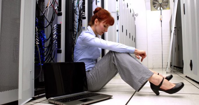 Stressed technician sitting on floor beside open server in high quality 4k format
