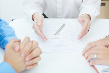 Young doctor explains how to fill out a medical form to young family. Partnership, trust and medical ethics concept