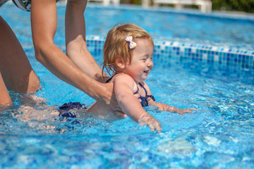 Baby girl learn to swim in pool  with her mother