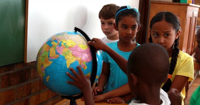 Pupils looking at the globe in classroom in elementary school