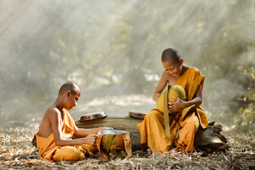 Buddhist monks are walking on a wooden bridge in mist sunrise