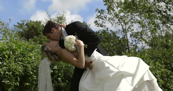 Groom kissing his pretty new wife outside