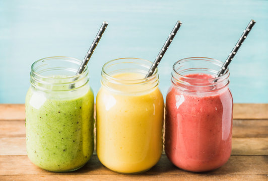 Three jars of fresh fruit smoothies with various colors and tastes. Green, yellow, red.