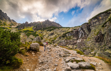 Mountain Landscape with Skok Waterfall with Tourists on Hiking Trail on Cloudy Day. Mlynicka Valley, High Tatra, Slovakia. © kaycco