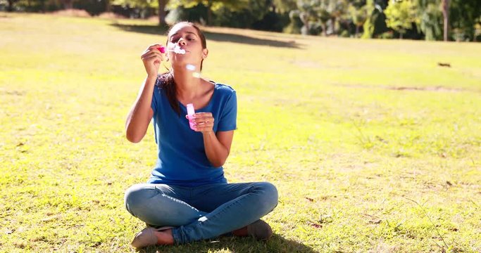 Pretty woman blowing bubbles in the park on a sunny day