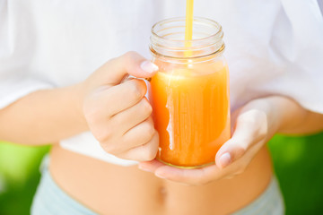Young woman holding a glass jar of fresh juice.
