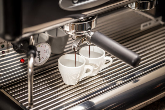 Espresso machine pouring coffee in white cups