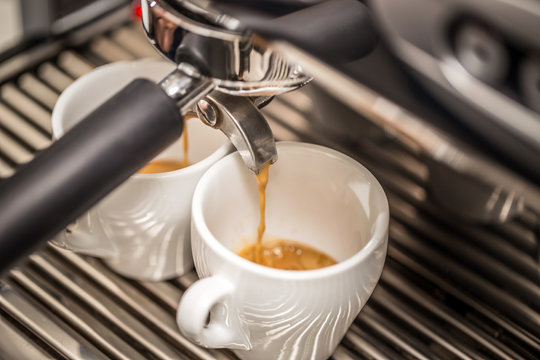 Espresso machine pouring coffee in white cups