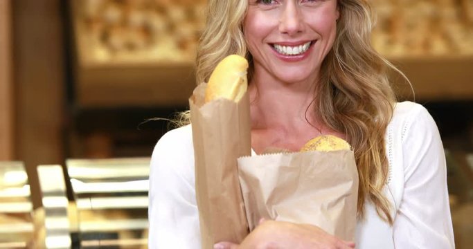 Portrait of smiling blonde holding paper bags in grocery store