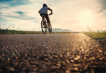Jongen rijdt op een fiets in het zonsonderganglicht