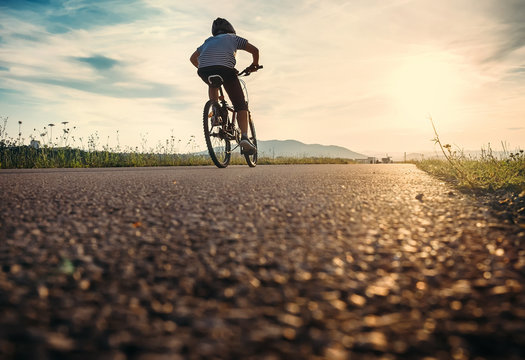 Boy rides a bicycle in the sunset light
