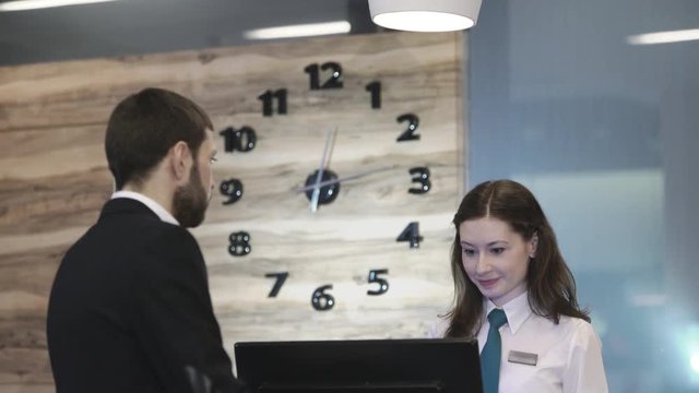 Businessman guest receives the key to the hotel room at the reception. Check-in time 12 p.m. UHD 4K