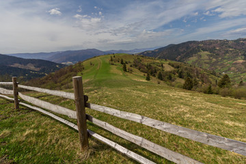 Fototapeta na wymiar Pasture in mountains and a wooden fence in the foreground. Carpa