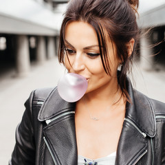 Beautiful young woman blowing bubble gum balloon