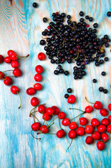 Black currant and cherries on blue wooden background