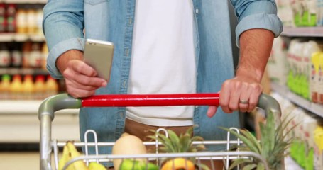 Senior man texting in the supermarket - Powered by Adobe