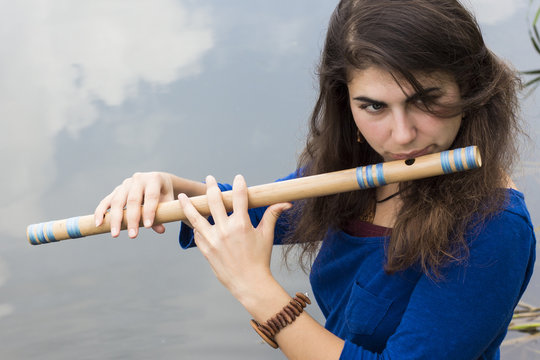 Musician playing a wooden flute on the banks of the river
