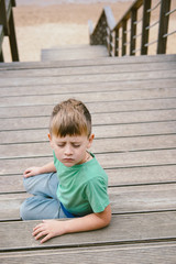 Boy 5 years ols sitting on a ladder with close eyes