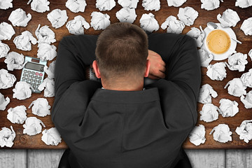 frustrated businessman with head on wooden desktop / frustrierter Geschäftsmann mit Kopf auf der...