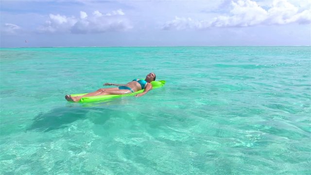 SLOW MOTION: Woman relaxing on inflatable water floatie in ocean
