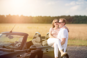 Verliebter Mann steht am Cabrio und trägt seine Frau - Verliebtes Pärchen am Auto 
