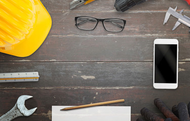 Construction site table with free space for text. Smart phone, helmet, paper, pencil, ruler,...