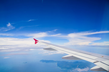 Wing of airplane flying above the clouds in the blue sky backgro