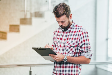 Young casual businesman working on checklist