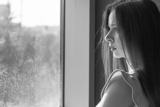 A girl looks out the window. Black and white photo.