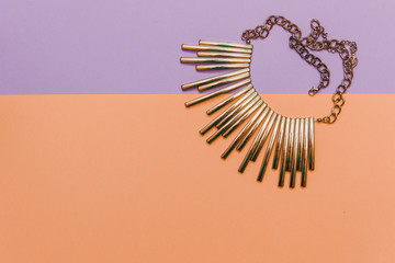 Flat lay fashion set: gold accessory for neck on pastel backgrounds.
