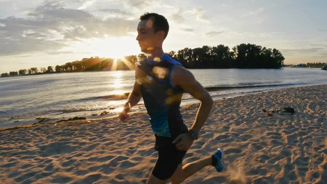 Strong male runner at the beach takes a break to get his breath back