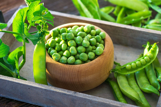 Bowl with fresh peas on a wooden background