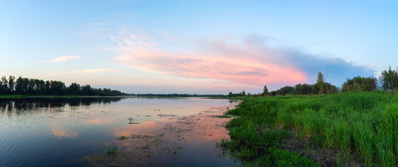 Pink clouds over a lake at sunset .Panorama.