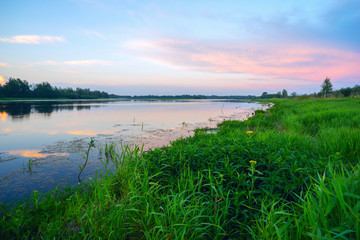 Pink clouds over a lake at sunset .