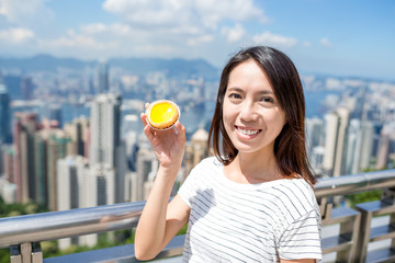 Woman holding local food in Hong Kong, egg tart