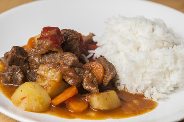 Beef stew with carrots and potatoes, served with white rice.
