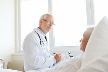 senior woman and doctor with clipboard at hospital