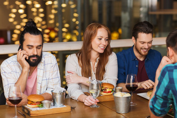 man with smartphone and friends at restaurant