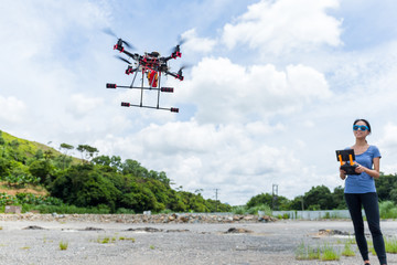 Fototapeta na wymiar Woman with remote control and flying surveillance drone