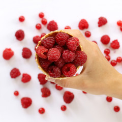 vitamin cocktail with fresh berries/ raspberries in a waffle cone, holding hand on the blurry background of red berries top view 