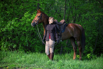 Beauty fashion model in equestrian hunt uniform posing with horse